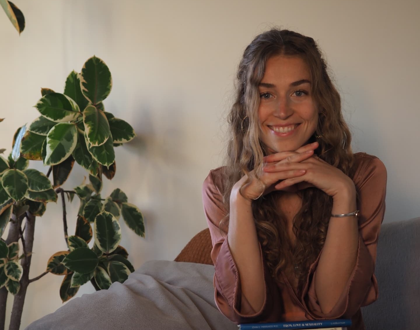 Anna-Lena sitting on a couch, smiling with her chin resting on her hands