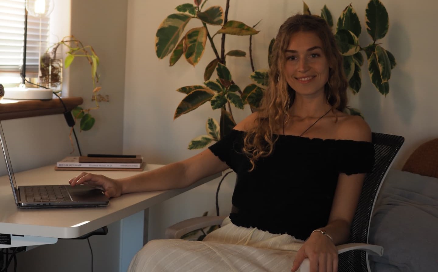 Anna-Lena sitting at a desk with her laptop, smiling, in her home office